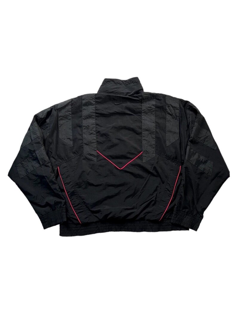 May include: Black vintage windbreaker jacket with a high collar and pink accent lines. The jacket features a chevron design on the back and striped detailing on the sleeves. A classic athletic-inspired outerwear piece.