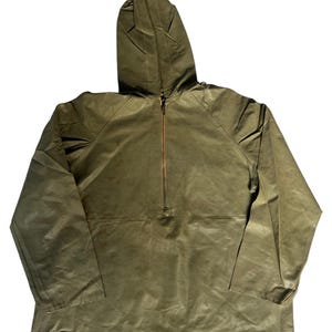 Może przedstawiać: Zielona kurtka z kapturem w kolorze oliwkowym z zapięciem na pół zamek. Kurtka ma długie rękawy i kaptur. Tkanina ma lekko teksturowany wygląd. Zamek błyskawiczny ma kontrastujący brązowy kolor.