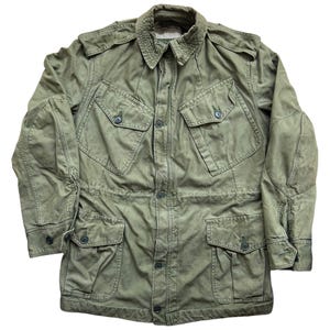 Puede incluir: Una chaqueta verde de estilo militar con múltiples bolsillos y cierres de botón.