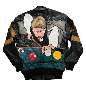 Könnte beinhalten: Schwarze Lederjacke mit farbenfrohem Billardszenen-Design auf dem Rücken. Die Jacke zeigt eine Grafik einer Person beim Billardspielen, mit Billardkugeln und einem grünen Billardtisch. Die Ärmel haben braune und schwarze Akzente.