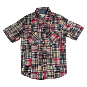 Op de afbeelding: Kort mouwen patchwork overhemd met een knoopsluiting. Het overhemd heeft een verscheidenheid aan ruitpatronen in rood, zwart, wit en geel. Het heeft twee voorzakken en een blauwe spijkerstof kraag.