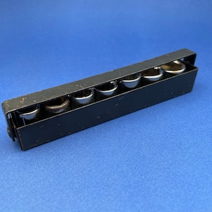 May include: A black metal socket wrench holder with seven silver sockets. The holder is on a blue background.
