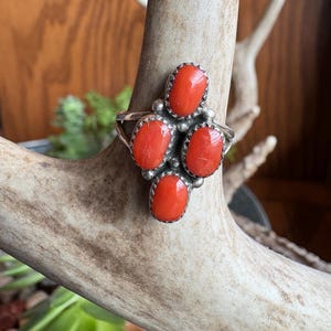 May include: A silver ring with four red coral stones set in a cluster design.