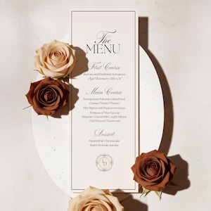 May include: A rectangular white menu card with black text featuring sections for First Course, Main Course, and Dessert, decorated with four roses in shades of cream and brown, placed on a circular white base with a thin black border.