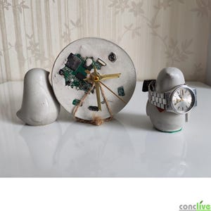 Peut inclure: Une horloge en béton unique avec un design de circuit imprimé, avec des aiguilles dorées. Un objet en forme d'oiseau en béton et un support de montre en forme d'oiseau avec une montre argentée complètent l'ensemble. L'horloge mesure environ 13 cm de diamètre.