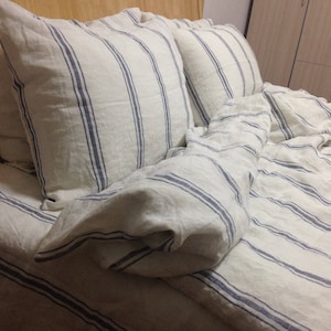 May include: White linen bedding with blue stripes. The bedding is made of a soft, comfortable material and is perfect for a bedroom.