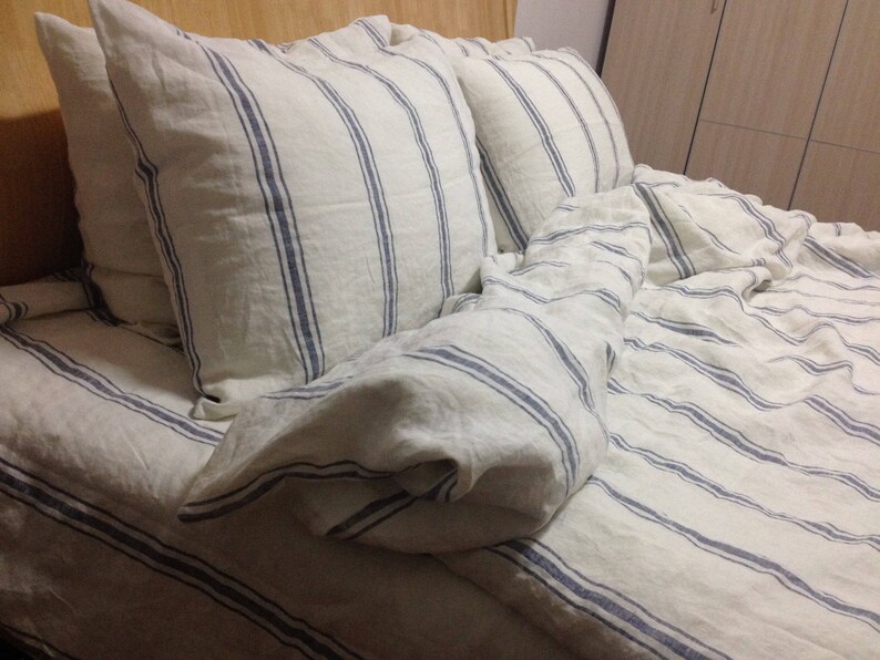 May include: White linen bedding with blue stripes. The bedding is made of a soft, comfortable material and is perfect for a bedroom.
