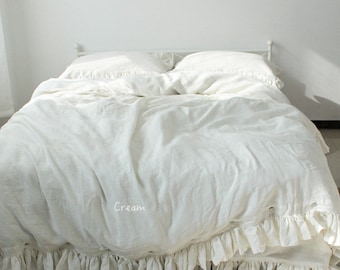 May include: White linen duvet cover with a ruffled edge and a cream colored label that says "Cream".