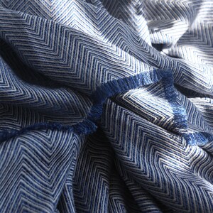 May include: Blue and white chevron patterned throw blanket with a fringed edge.