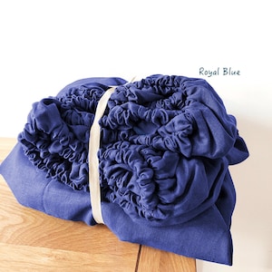 May include: A bundle of royal blue fabric with a white ribbon tied around it. The fabric is gathered and bunched up, creating a soft and textured look.
