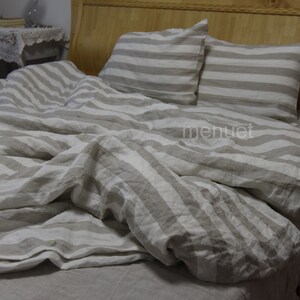 May include: A white and beige striped linen duvet cover and two matching pillowcases. The duvet cover is folded back to reveal the beige linen fabric underneath.