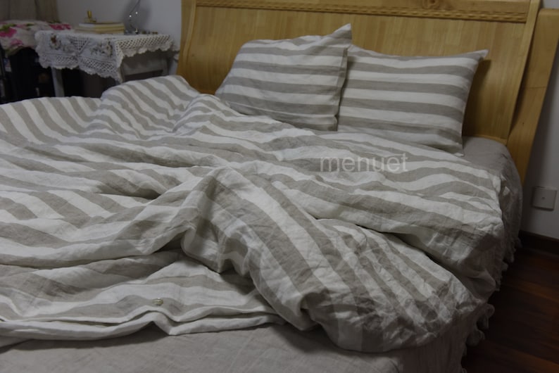 May include: A white and beige striped linen duvet cover and two matching pillowcases. The duvet cover is folded back to reveal the beige linen fabric underneath.