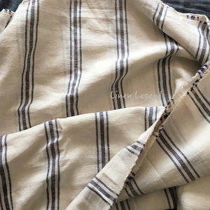 May include: A close-up of a white linen fabric with blue stripes. The fabric is folded and has a raw edge. The text "Linen Legend" is visible in the image.