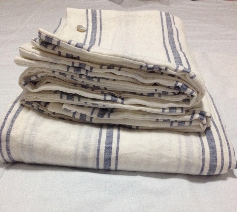 May include: A white and blue striped linen bedding set folded on a white surface.