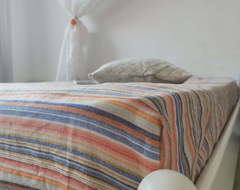May include: A striped bed sheet with a white bed frame. The sheet is made of a soft, natural fabric and has a relaxed, casual look.