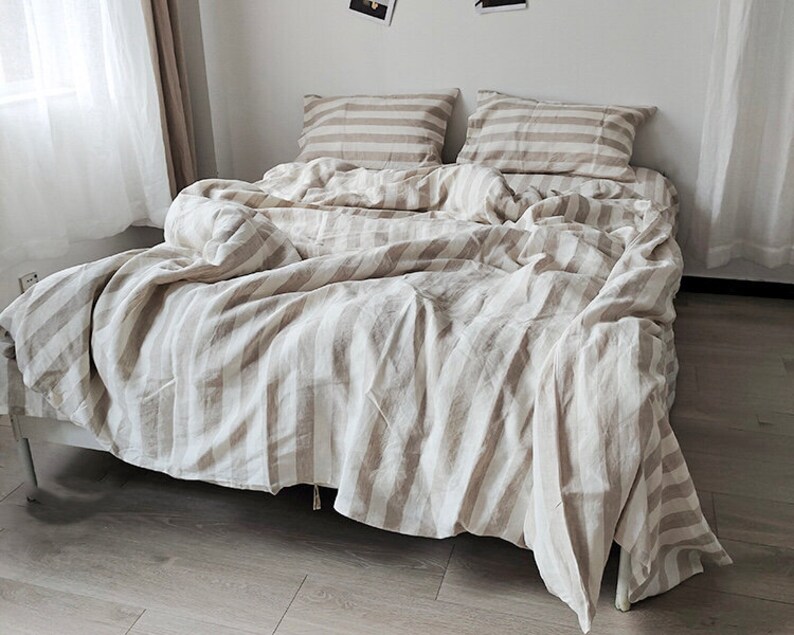 May include: A white and beige striped linen bedding set with a duvet cover, two pillowcases, and a flat sheet.