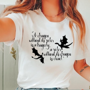 Puede incluir: Camiseta blanca con un diseño de dragón negro y la cita: "Un dragón sin su jinete es una tragedia, un jinete sin su dragón está muerto". La palabra "WHITE" está en la parte inferior.