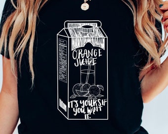 Può includere: Maglietta nera con una grafica bianca di un cartone di succo d'arancia che dice "Orange Juice It's Yourself You Want It".