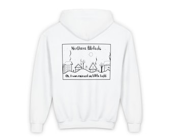 Puede incluir: Sudadera con capucha blanca con un estampado gráfico en blanco y negro en la parte posterior. El gráfico presenta una escena de invierno con casas, árboles y un muñeco de nieve. El texto "Northern Attitude" y "Oh, I was raised on little light" está impreso debajo del gráfico.