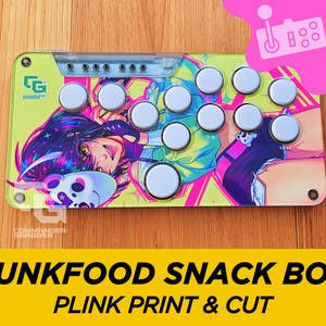 Puede incluir: Un panel de control de arcade verde y amarillo con un gráfico de estilo anime colorido que presenta un personaje femenino con cabello rosa y azul. El panel tiene 10 botones blancos y el texto "Commander Gripper" está impreso en la esquina inferior izquierda.