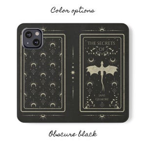 May include: Black phone case with a pattern of moons and stars. The back of the case features a white dragon with the text "The Secrets of Jane Gilmore".