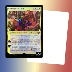May include: Commodore Guff, a legendary planeswalker card from the Magic: The Gathering trading card game. The card features a yellow background with a gold border and a picture of a wizard with a red beard and a purple robe. The card text describes the planeswalker's abilities, including creating a 1/1 red Wizard creature token and dealing damage to opponents.