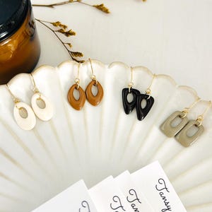 Puede incluir: Juego de tres tazas de cerámica con acabado mate moteado. Las tazas son de color crema, gris claro y gris oscuro. Cada taza tiene un diseño simple y minimalista.