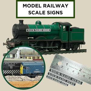 May include: A green and black model train with the text "YOUR NAME HERE" on the side. The image also includes a ruler and several small labels with the text "YOUR NAME HERE". The text "MODEL RAILWAY SCALE SIGNS" is at the top.