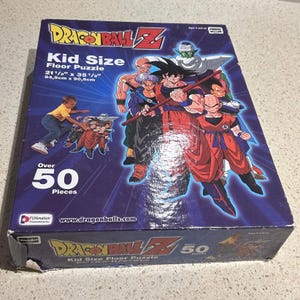 Könnte beinhalten: Eine Kid Size Dragon Ball Z Bodenpuzzle-Box. Die Box zeigt farbenfrohe Illustrationen von Charakteren aus der Anime-Serie. Das Puzzle ist 54,5 cm x 90,5 cm groß und hat über 50 Teile. Auf der Box steht "Dragon Ball Z" und "Kid Size Floor Puzzle".