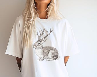 May include: White t-shirt with a graphic print of a grey rabbit with antlers.