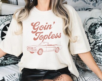 May include: A white t-shirt with a red graphic of a vintage convertible car and the text "Goin' Topless".
