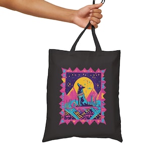 May include: Black tote bag with a colorful graphic of a wolf howling at the moon in a desert landscape. The graphic features a pink, blue, and yellow color scheme with geometric patterns.