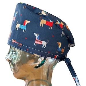 Könnte beinhalten: Eine blaue OP-Mütze mit einem Muster aus bunten Dackeln. Die Mütze hat einen Band am Rücken.