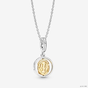 May include: A silver chain necklace featuring a circular pendant with a gold-toned center disc. The gold disc is embossed with the text 'PLATFORM 9 3/4' and is framed by a silver ring. The pendant hangs from a silver bail marked with 'ALE' and 'S925'.