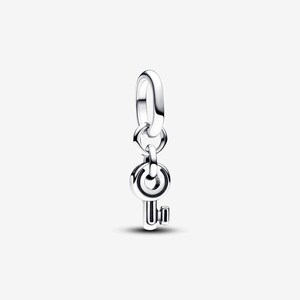 May include: A polished sterling silver charm shaped like a small key, featuring a circular head with a central cutout and a short, rectangular bit. The charm hangs from a smooth, oval-shaped jump ring, designed to be attached to a bracelet or necklace.