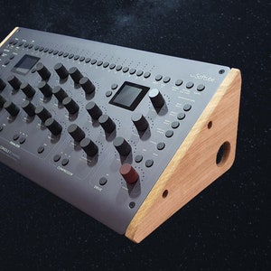 Könnte beinhalten: Ein graues Audiomischpult mit zahlreichen Knöpfen, Reglern und zwei kleinen Bildschirmen. Die Konsole hat Holzseitenteile und der Text "Softube" ist sichtbar. Die Konsole ist mit "Console 1 Channel" beschriftet.