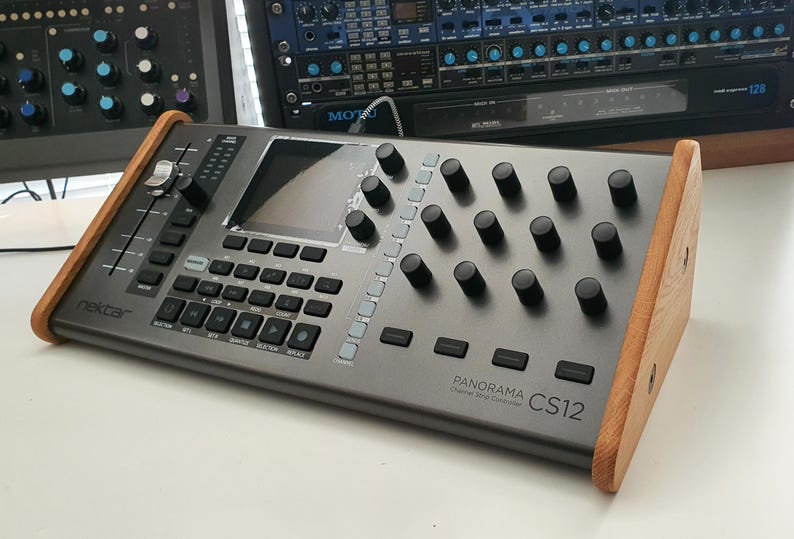 Puede incluir: Un controlador DAW Nektar Panorama CS12 Chrome con un panel lateral de madera. El controlador tiene una pantalla, botones y perillas.