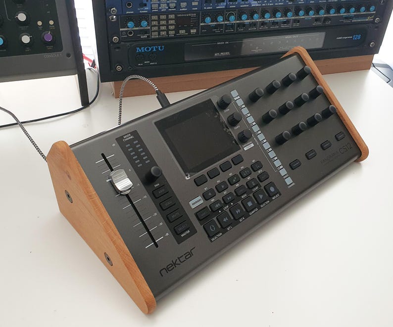 Puede incluir: Un controlador de teclado MIDI Nektar Impact LX25+ gris con un soporte de madera. El controlador tiene una pantalla grande, faders, perillas y botones. El teclado tiene 25 teclas.