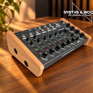 May include: A black audio mixer console featuring multiple rotary knobs, buttons, and input ports, encased in light-coloured wooden side panels. The device includes labels for various functions and the text Synths & Wood The Aesthetics of Sound.
