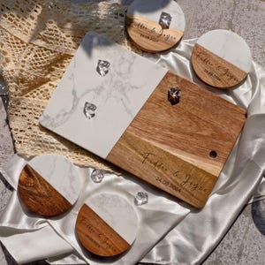 May include: A set of four white and brown marble coasters and a white and brown marble serving board. The coasters and serving board are engraved with the text "Fidder & Joyce" and the date "24.08.2024".