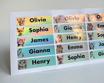 May include: Sheet of personalized name labels with animal illustrations. Each label features a name in black text, such as "Olivia" and "Sophia", above a colorful background and a small animal image, like a tiger or fox.