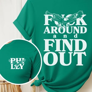 May include: Green t-shirt with a white eagle graphic and the text "F**k Around and Find Out".