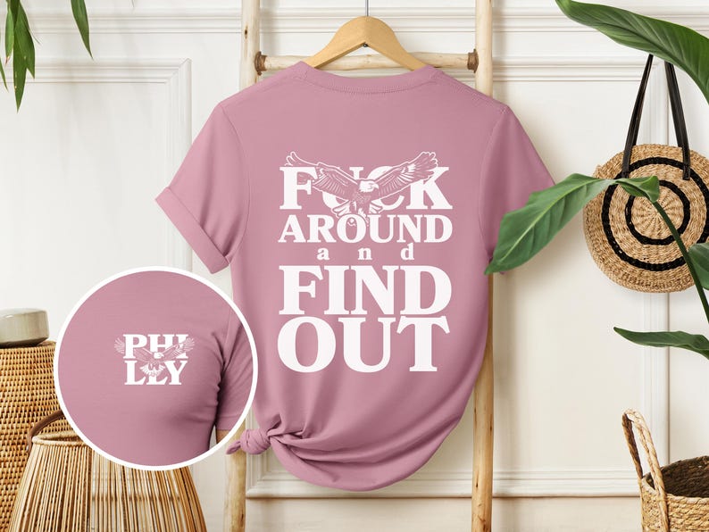 May include: A pink t-shirt with a white eagle graphic and the text "F**k Around and Find Out".