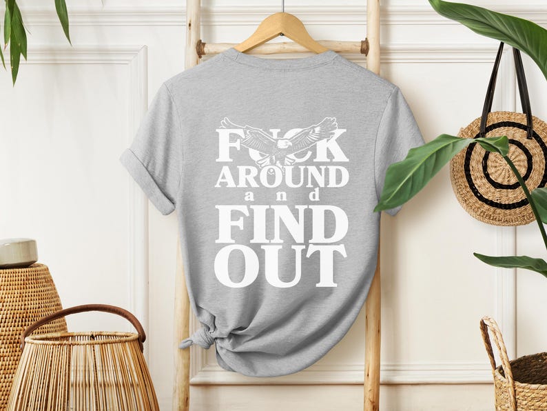 May include: Gray t-shirt with a white graphic print that says "F**k Around and Find Out" with a stylized eagle design.