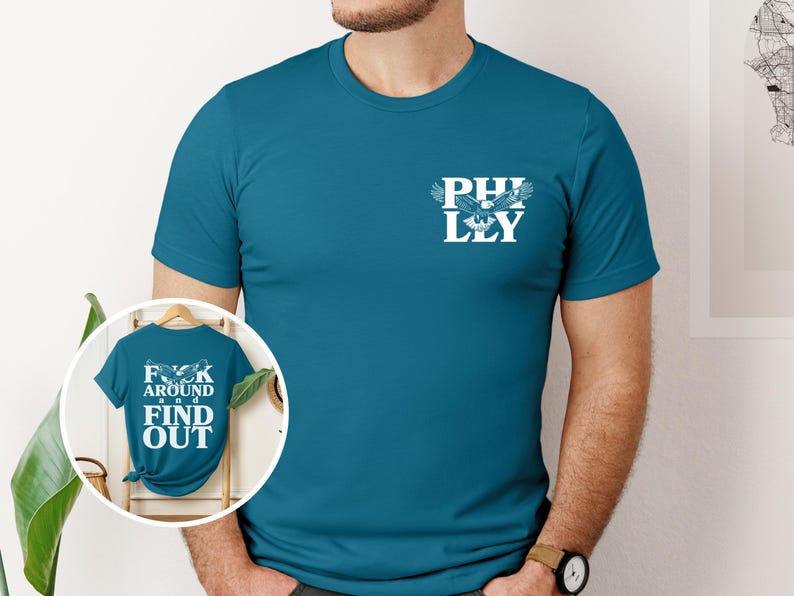 May include: A teal blue t-shirt with a white eagle graphic and the text "PHILLY" on the front. The back of the shirt has the text "F**K AROUND AND FIND OUT".