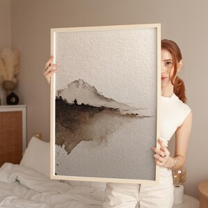 A minimal abstract landscape watercolor print in earthy brown and beige tones on textured paper, showcasing a serene wabi-sabi aesthetic. The subtle gradient and soft edges create a calming, organic feel. Displayed in a cozy bedroom setting, perfect for minimalist or rustic wall art.