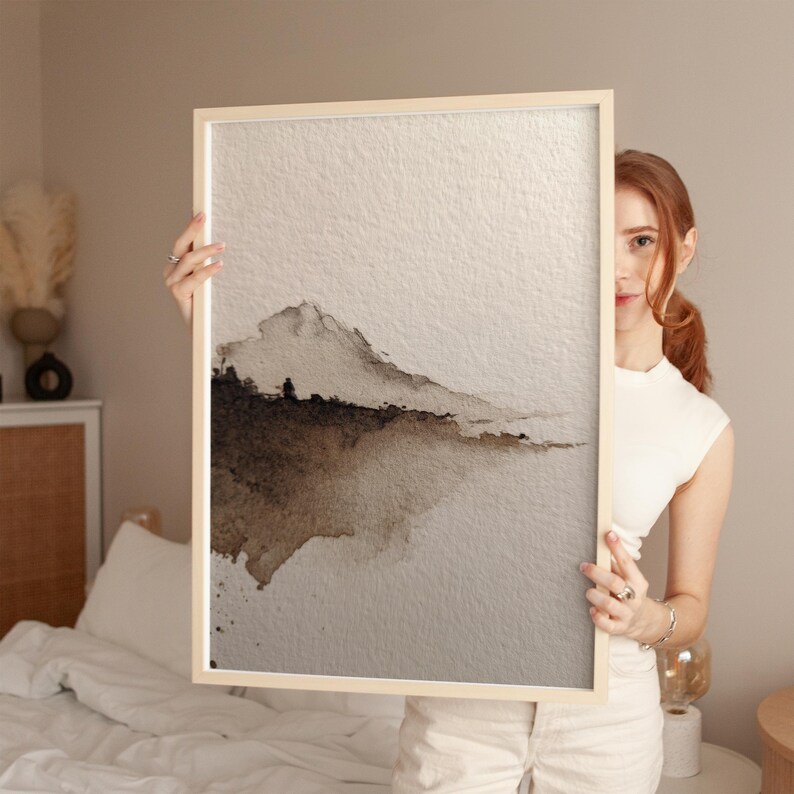 A minimal abstract landscape watercolor print in earthy brown and beige tones on textured paper, showcasing a serene wabi-sabi aesthetic. The subtle gradient and soft edges create a calming, organic feel. Displayed in a cozy bedroom setting, perfect for minimalist or rustic wall art.