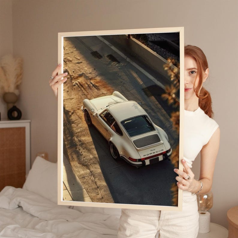 A vintage Porsche 911 captured in warm, golden-hour lighting highlights its classic curves and timeless design. This automotive wall art print features nostalgic, earthy tones and soft shadows, perfect for classic car enthusiasts. Displayed in a cozy bedroom, it adds a sophisticated touch to car decor.