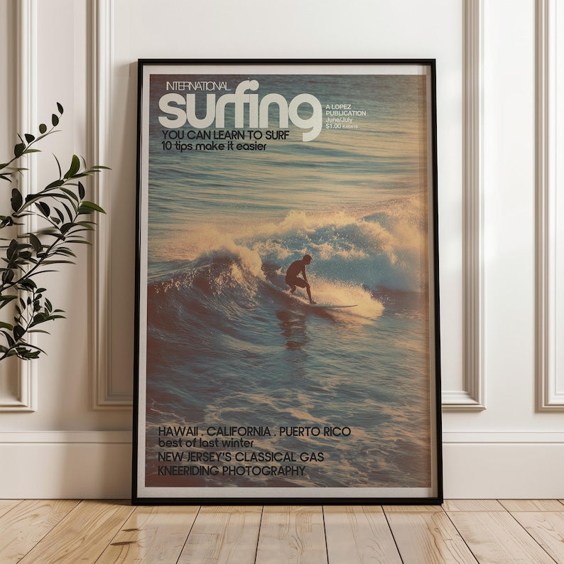 Vintage surf poster featuring a lone surfer riding a sunlit wave with soft pastel ocean tones and retro typography. The artwork evokes a classic coastal vibe inspired by mid-century surf magazines. Displayed leaning against a white paneled wall in a bright room, it adds nostalgic surf charm to the space.