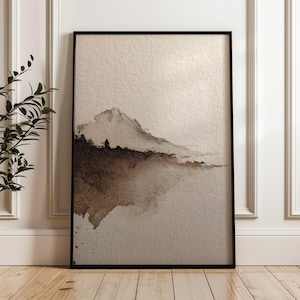 Abstract landscape art print in a minimal wabi-sabi style with earthy brown and beige watercolor tones on textured paper. The serene and calming design rests against a white paneled wall, perfect for minimalist or rustic interior decor. This peaceful wall art enhances the ambiance of a modern living space.